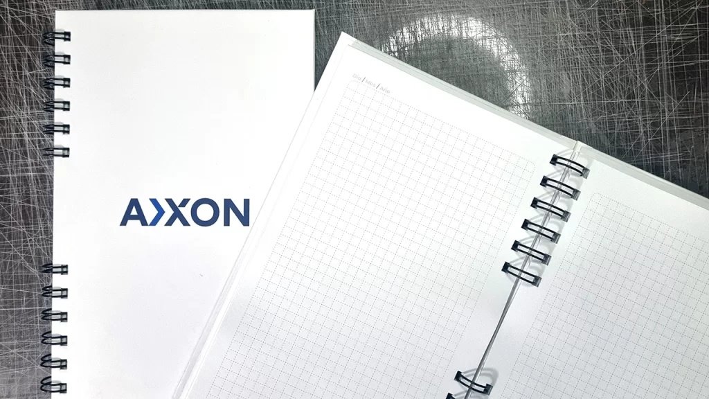 Cuaderno personalizado de pasta dura con el logotipo de Axxon impreso en la portada.